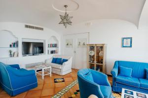 a living room with blue chairs and a tv at Hotel Cetus in Cetara