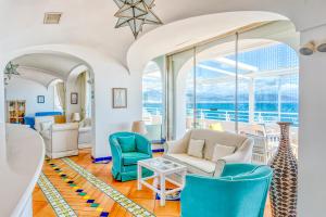 a living room with white furniture and large windows at Hotel Cetus in Cetara