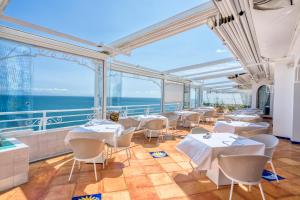 a restaurant with white tables and chairs and the ocean at Hotel Cetus in Cetara
