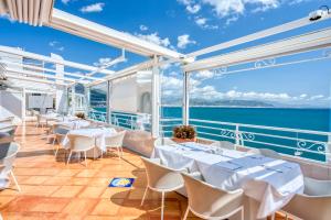 a restaurant with white tables and chairs and the ocean at Hotel Cetus in Cetara
