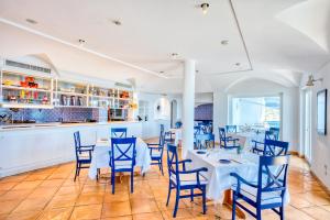 a dining room with white tables and blue chairs at Hotel Cetus in Cetara