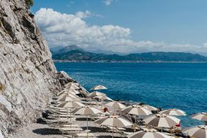 a group of umbrellas on a beach next to the water at Hotel Cetus in Cetara
