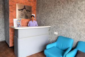um homem parado atrás de um balcão com duas cadeiras azuis em DJ CITI INN HOTEL em Kuala Terengganu
