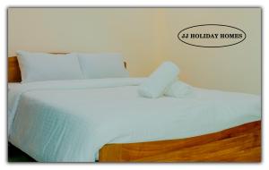 Una cama con sábanas blancas y un cartel que lee casas de Hollywood en JJ Holiday Homes en Canaguinim