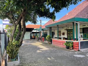 a building with a tree next to a street at Pamularsih Homestay in Yogyakarta