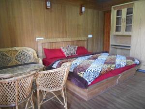 1 dormitorio con 1 cama, mesa y sillas en Nandan Kanan Auli Resort, en Jyotirmath
