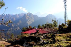 a house with a red roof on top of a mountain at Nandan Kanan Auli Resort in Joshīmath