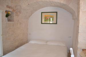 um quarto com uma cama branca numa parede de pedra em Conversa De Amicis n°8 em Alberobello