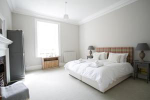 a white bedroom with a large white bed and a fireplace at Auldhame House East Wing, Seacliff in North Berwick