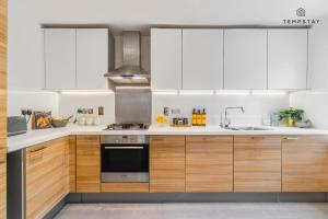 a kitchen with wooden cabinets and a stove top oven at STYLISH 4 BED FAMILY HOME AT MADEJSKI, READING UNIVERSITY in Reading