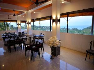 uma sala de jantar com mesas, cadeiras e janelas em The Tamarind Tree Hotel em Port Blair