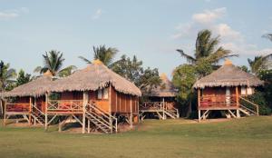 un grupo de cabañas con techos de paja y palmeras en Vila Itaqui, en Luís Correia