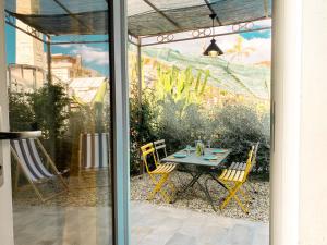 een patio met een tafel en stoelen en een muurschildering bij New Agriloft 1 Nursery, giardino, clima e Wi-Fi a 50 mt dal mare in Bordighera
