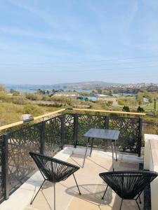 a patio with two chairs and a table on a balcony at Artro House in Pembrokeshire