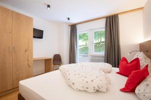 Habitación de hotel con cama con almohadas rojas en Haus Christian en Nova Levante