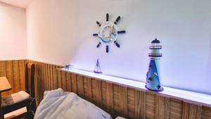a shelf with a clock and a lighthouse on it at Ap Anjos de Arraial - Residencial de frente para a Praia dos Anjos - Arraial do Cabo in Arraial do Cabo