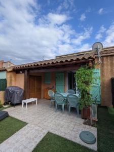 eine Terrasse mit Tisch und Stühlen vor einem Haus in der Unterkunft MARINES DU ROUSSILLON Villa en résidence avec piscine à 150 m de la plage v100 in Saint-Cyprien