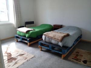 2 camas individuales en una habitación con ventana en REFUGIO Puerto Natales, en Punta Arenas