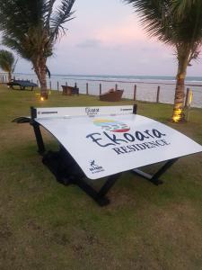 a surfboard sitting on the grass next to the ocean at Ekoara Residence in Porto De Galinhas