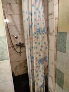 a shower curtain with blue flowers on it in a bathroom at Sobe Kuzmanović - Šabac in Šabac