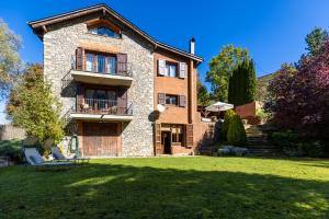 ein großes Steinhaus mit Rasen davor in der Unterkunft Casa El Molí de Bor a Cerdanya in Bor