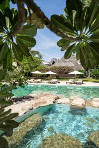 a swimming pool with blue water and rocks and umbrellas at Lion in the Sun Billionaire Retreat Malindi in Malindi