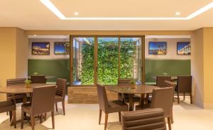 a dining room with tables and chairs and a large window at Hotel Annamar Premium in João Pessoa