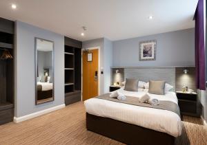 a bedroom with a large bed and a mirror at Hogs Back Hotel & Spa in Farnham