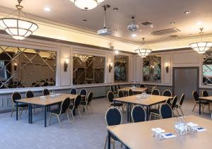 uma sala de jantar com mesas, cadeiras e janelas em Hogs Back Hotel & Spa em Farnham