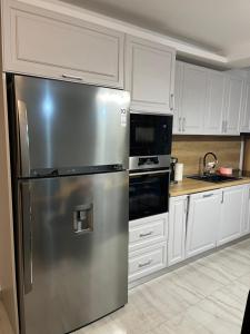 a stainless steel refrigerator in a kitchen with white cabinets at Casa IANIS Turda in Turda +10 photos