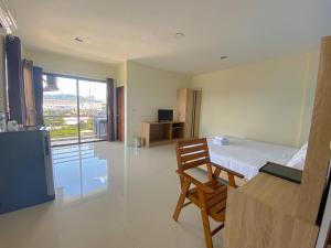 a bedroom with a bed and a table and a chair at Tha-ruea Residence in Thalang