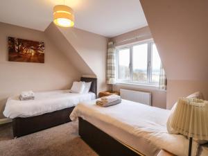 two beds in a room with two windows at Holly House in Spean Bridge
