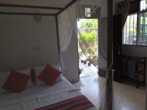 a bedroom with a bed with red and white pillows at Rusara Guest Home in Weligama