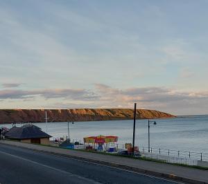 a road next to a body of water with a beach at Daffodil Guest House in Filey