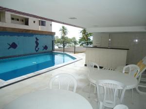 a swimming pool with white tables and chairs next to a white table and chairs at Apartamento Boa Viagem in Recife