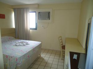 a small room with a bed and a table and chair at Apartamento Boa Viagem in Recife