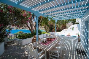 a white table and chairs under a blue pergola at The Big Blue in Órmos Aiyialís