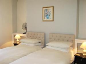 a bedroom with a white bed with two pillows at Dunedin Guest House in Penzance