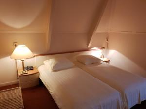 a bedroom with a large white bed with a lamp at Boetiek Hotel Marum in Marum