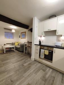 a kitchen with white cabinets and a living room at Cosy Riverside Apartment - FREE PARKING in York