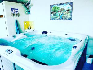 a bath tub filled with blue water in a bathroom at Le Coteau de Bazeille Spa & Sauna in Sainte-Bazeille