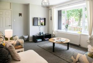 - un salon avec un canapé, une table et une fenêtre dans l'établissement Comfy 3-Bed House near City Centre, sleeps 6, à Tile Hill