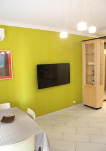 uma sala de jantar com uma parede verde e uma televisão de ecrã plano em Soraya em Nápoles
