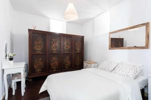 a bedroom with a white bed and a wooden cabinet at Casa tradicional Canaria en La Laguna centro in La Laguna