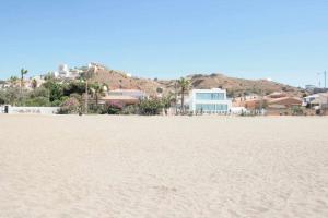 a sandy beach with houses and palm trees in the background at Mshome Mirada al Mediterráneo in Rincón de la Victoria