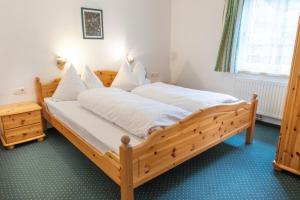 1 dormitorio con cama de madera con sábanas blancas en Appartmenthaus Bachler, en Haus im Ennstal