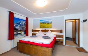 1 dormitorio con 1 cama con cortinas rojas y ventana en Hotel - Pension Alpenstern, en Schönau am Königssee