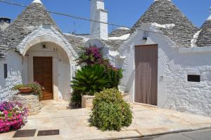 a white building with flowers in front of it at Trulli Aia Piccola in Alberobello