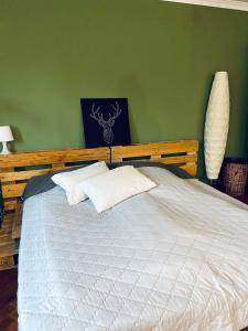 ein Schlafzimmer mit einem weißen Bett und einer grünen Wand in der Unterkunft Großes Ferienzimmer Uckermark in Casekow