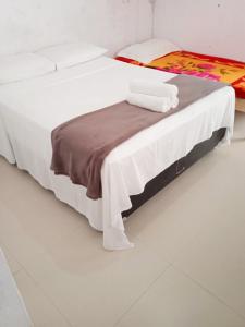 Una cama blanca con una manta marrón en una habitación en Studio em Arraial, en Arraial do Cabo